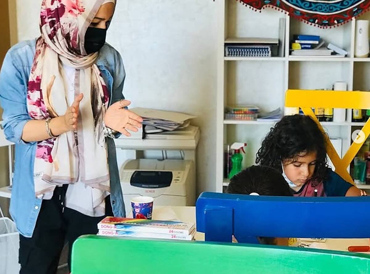 An instructor guiding a young student at a studio desk