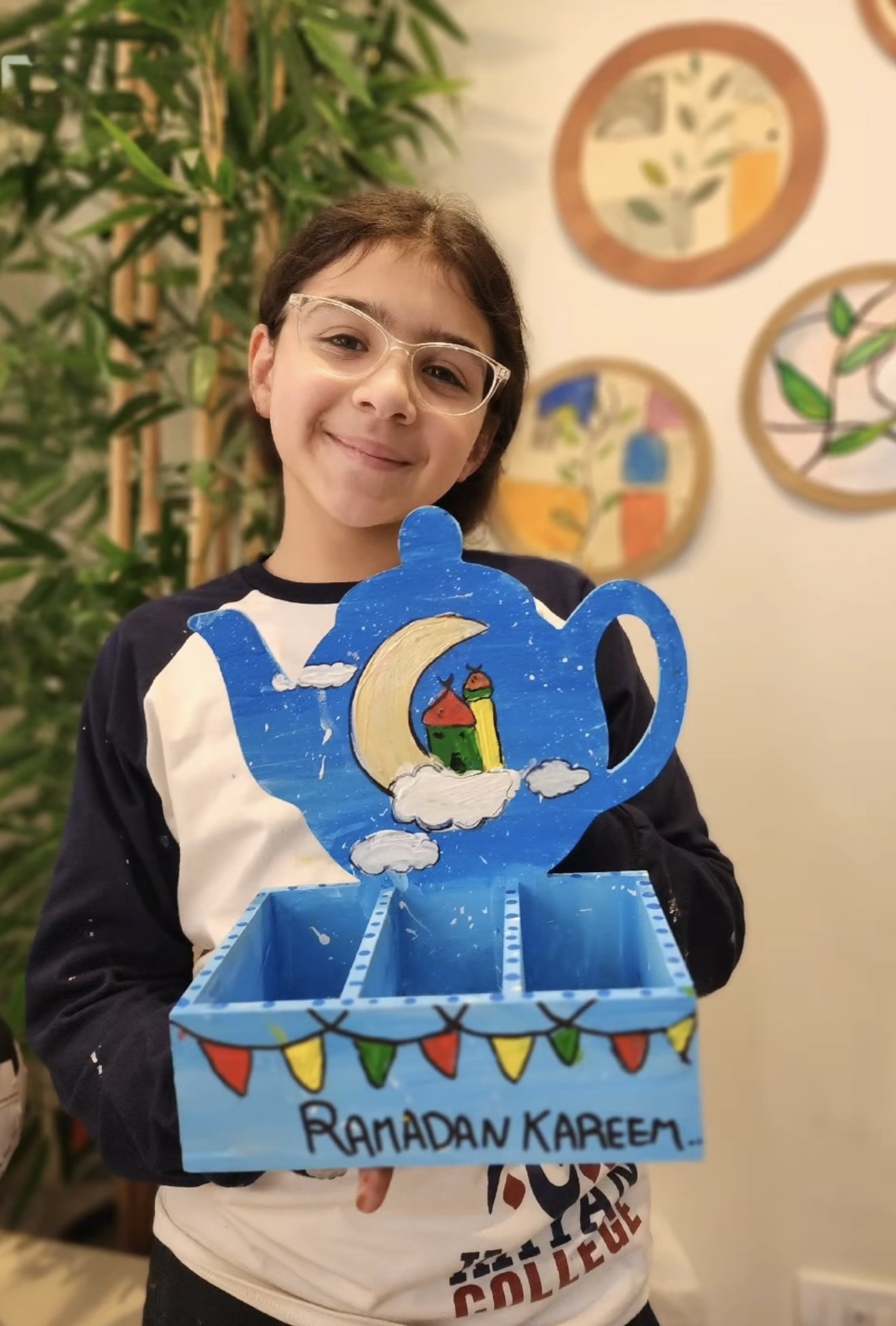 A student holding a pastel drawing of three lit candles